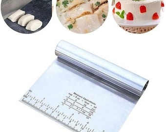 Peut inclure: Une spatule à pâtisserie en acier inoxydable avec une règle et des conversions de mesure pour les tasses, les cuillères à soupe et les millilitres. La spatule a une poignée arrondie et une lame plate rectangulaire.