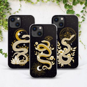 May include: Three black iPhone cases with different designs featuring gold snakes, moons, stars, and floral elements. The designs are inspired by mystical and spiritual themes.