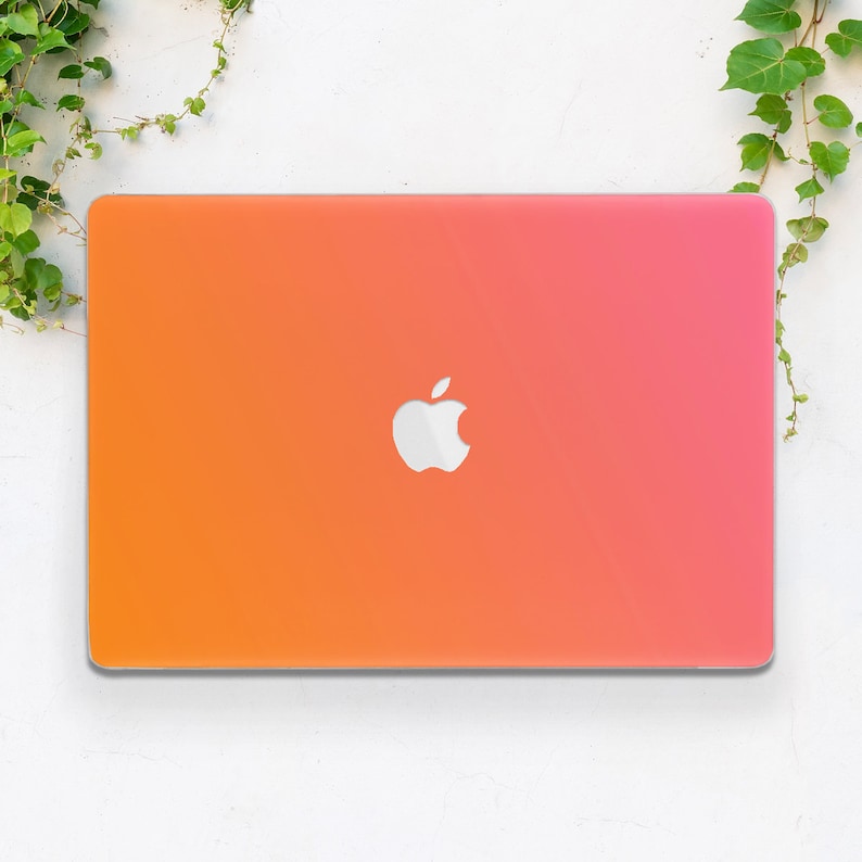May include: A laptop computer with a gradient orange and pink colored cover. The Apple logo is visible on the cover.