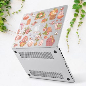 May include: A silver laptop with a variety of colourful stickers featuring cartoon animals, flowers, and food. The stickers are arranged in a whimsical pattern on the laptop's lid.