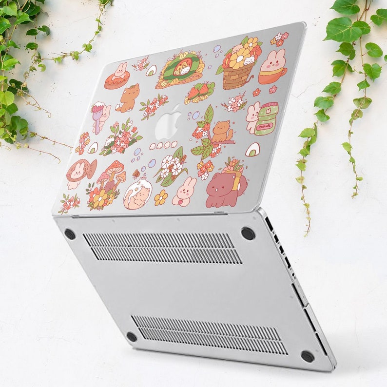 May include: A silver laptop with a variety of colourful stickers featuring cartoon animals, flowers, and food. The stickers are arranged in a whimsical pattern on the laptop's lid.