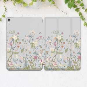 May include: A floral patterned case for a tablet. The case is made of two pieces that snap together. The pattern features a light blue background with pink, white, and green flowers and birds.