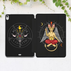 May include: Black iPad case featuring a goat head within a pentagram, with the text "Lilith". The other side shows a winged cat-like figure with a flame, seated in a lotus position, with crescent moons.