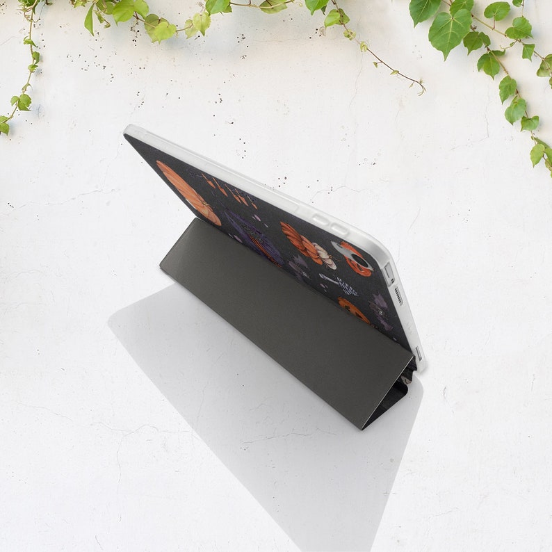 May include: A black and white tablet case with a floral design. The case is closed and folded into a stand position.