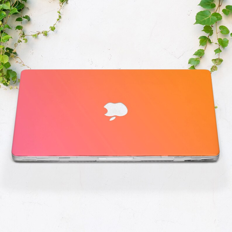 May include: A laptop computer with a pink to orange gradient color scheme. The Apple logo is visible on the lid.