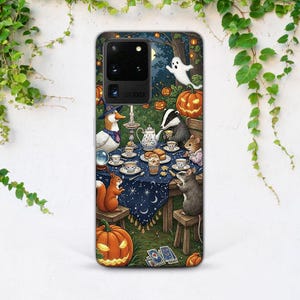 May include: A phone case with a Halloween-themed illustration. A duck in a witch's hat, a badger, and other animals are at a tea party. Pumpkins, a ghost, and a starry night sky are also depicted in the design.