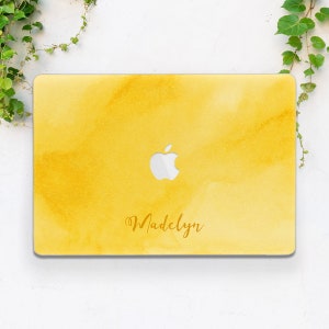 May include: Yellow laptop skin with a watercolor design and the name "Madelyn" printed in gold lettering.