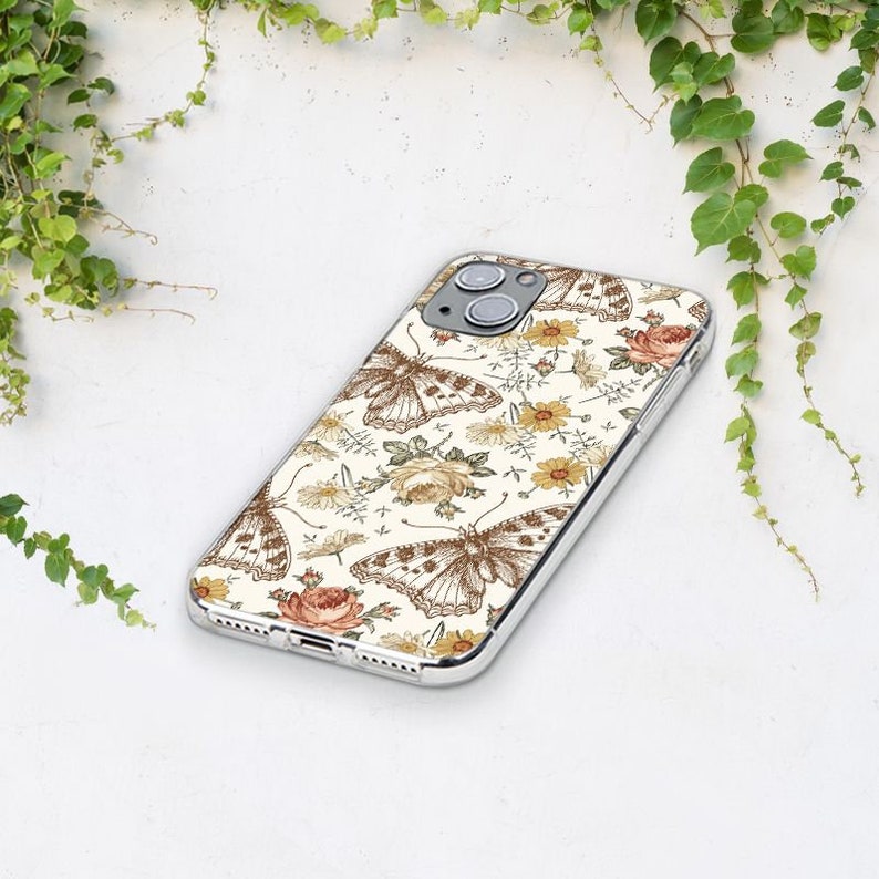 May include: Transparent phone case with a cream backdrop, adorned with a repeating pattern of brown butterflies and floral designs in yellow and peach hues. The case has a clear border and covers the phone's back and sides.