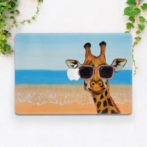 以下が含まれることがあります： 青い水と白い砂浜のビーチで、ピンクのサングラスをかけたキリンの絵が描かれた、ラップトップのスキンのデザインです。