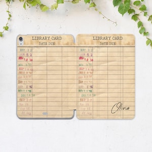 May include: A tablet case featuring a vintage library card design with a beige, paper-like texture. The print includes the text LIBRARY CARD and DATE DUE, with columns of stamped dates in various colors. The name Olivia is printed in black script.
