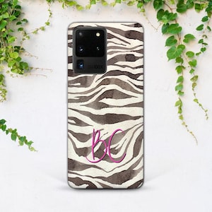 Może przedstawiać: Etui na telefon z wzorem w zebrę w odcieniach brązu i bieli. Etui posiada różowy monogram z literami "BC". Etui na telefon posiada moduł aparatu i lampy błyskowej u góry.