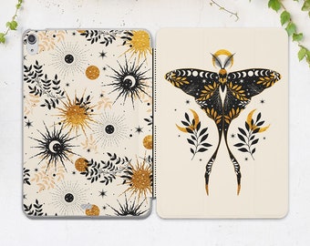 May include: A white phone case with a black and gold design. One side features a repeating pattern of suns, moons, and stars. The other side features a black moth with gold accents and a crescent moon design.
