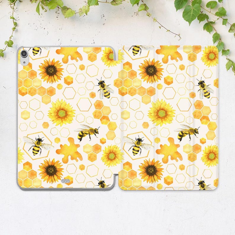 K&ouml;nnte beinhalten: Eine wei&szlig;e Tablet-H&uuml;lle mit einem sich wiederholenden Muster aus gelben Sonnenblumen, Bienenwaben und Bienen. Die H&uuml;lle ist ge&ouml;ffnet und zeigt das Innendesign. Das Design ist im Aquarellstil mit hellem Cremefarbenem Hintergrund.