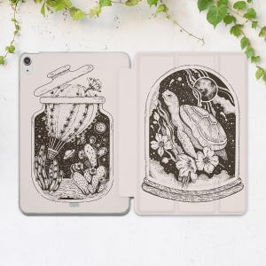 May include: A black and white illustration of a cactus in a glass jar with a lid, and a turtle in a glass dome with flowers and a moon. Both jars are filled with stars and planets.