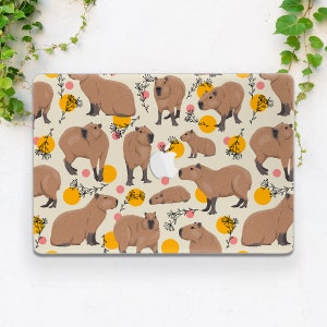 May include: A laptop skin with a repeating pattern of capybaras on a cream background. The capybaras are brown and are in various poses. The background is accented with yellow and pink circles and black floral designs.