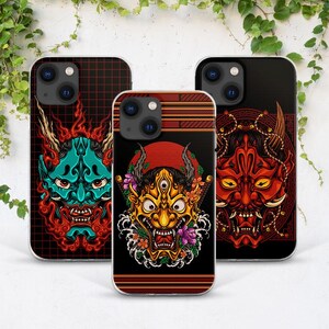 Peut inclure: Trois coques de téléphone avec des motifs différents représentant des masques de démons japonais. La première coque présente un masque de démon bleu avec des flammes rouges, la deuxième coque présente un masque de démon doré avec des fleurs et la troisième coque présente un masque de démon rouge sur fond noir.