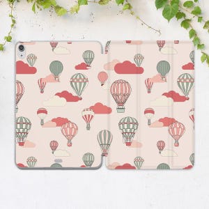 May include: A pink iPad case with a pattern of hot air balloons and clouds. The balloons are in shades of pink, green, and white.