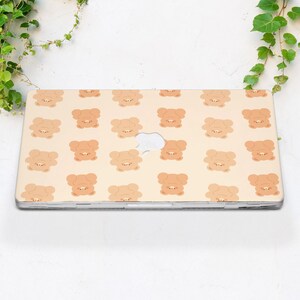 May include: A beige laptop skin with a repeating pattern of brown cartoon bears. The bears are facing forward with their paws in the air.