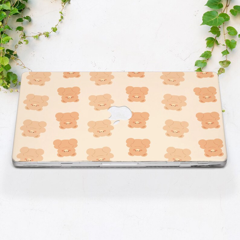 May include: A beige laptop skin with a repeating pattern of brown cartoon bears. The bears are facing forward with their paws in the air.