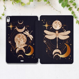 Könnte beinhalten: Eine schwarze und goldene iPad-Hülle mit einem geometrischen Design mit einer Libelle, Monden und Sternen. Die Hülle hat eine Klappe, die den Bildschirm bedeckt.