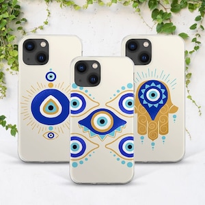 May include: Three clear phone cases with different designs featuring the evil eye symbol in blue and gold. The evil eye symbol is a popular amulet in many cultures, believed to ward off bad luck and protect against negative energy.