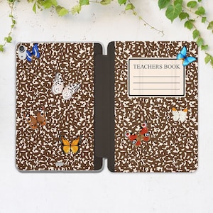 May include: A brown and white notebook cover with a butterfly design. The cover has the words "TEACHERS BOOK" printed on it.
