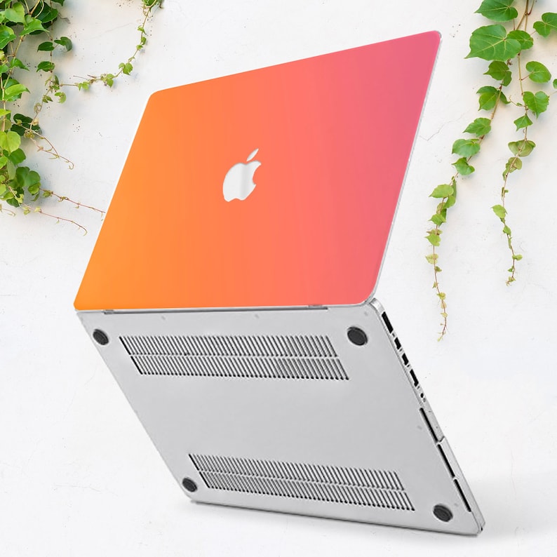 May include: A silver laptop with a gradient orange and pink cover. The laptop is closed and the Apple logo is visible on the cover.