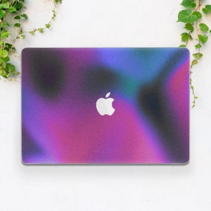 May include: A laptop computer with a purple, blue and black iridescent design. The Apple logo is visible on the lid.