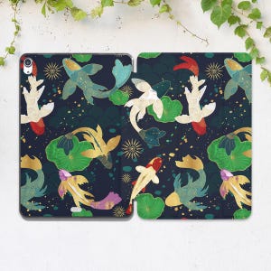 May include: A navy blue tablet case featuring a repeating pattern of koi fish, lily pads, and starbursts. The koi are in shades of gold, white, red, and teal. The lily pads are green, and the starbursts are gold.