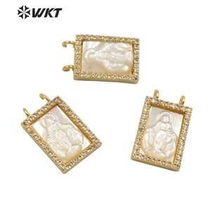 May include: Three gold-toned pendants with a white mother-of-pearl inlay featuring a religious image. Each pendant is surrounded by clear rhinestones.