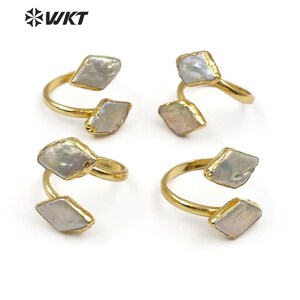 Puede incluir: Cuatro anillos de oro con dos piedras blancas nacaradas en cada anillo. Los anillos son abiertos y tienen un diseño retorcido.