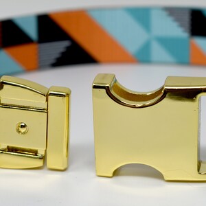 May include: A gold metal buckle with a turquoise, orange, and black geometric patterned dog collar.