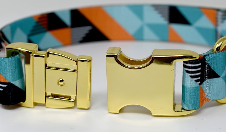 May include: A gold metal buckle with a turquoise, orange, and black geometric patterned dog collar.