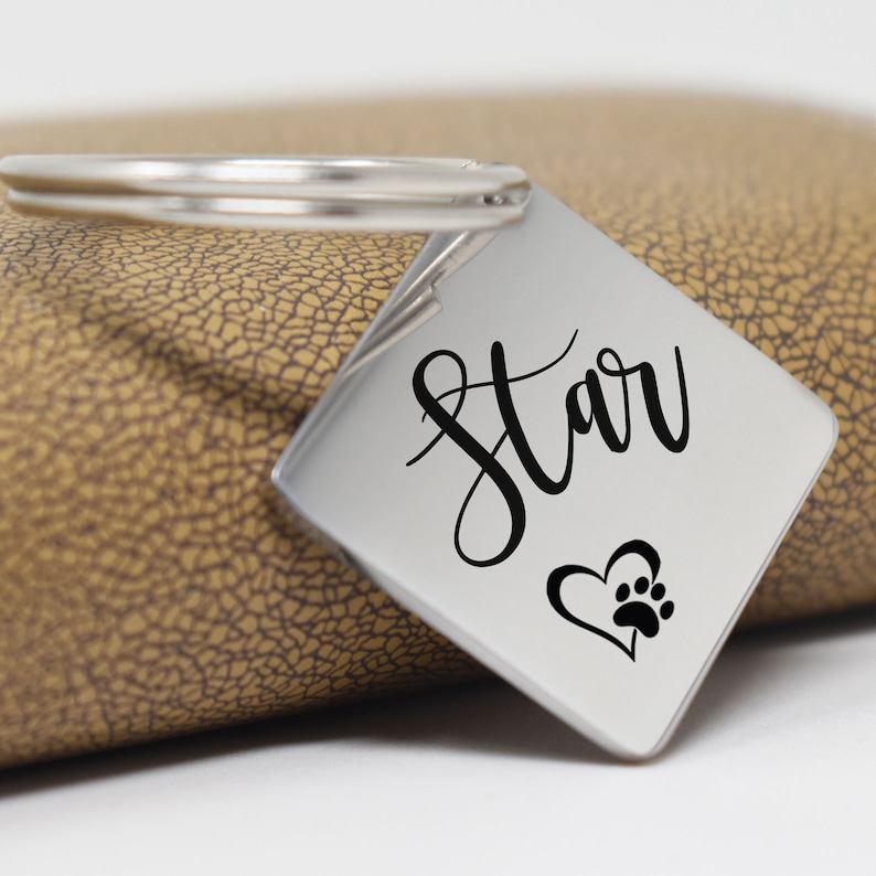 May include: Silver keychain with a square tag that says "Star" in cursive with a paw print inside a heart.