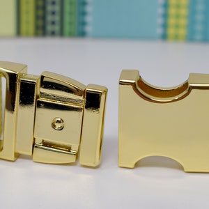 Puede incluir: Una hebilla de metal dorado para un collar de perro. La hebilla est&aacute; abierta y lista para ser fijada a un collar.