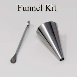 May include: A stainless steel funnel kit with the text "Funnel Kit" at the top. The kit includes a conical funnel and a small, long spoon-like tool. The funnel is silver and has a narrow opening at the bottom.