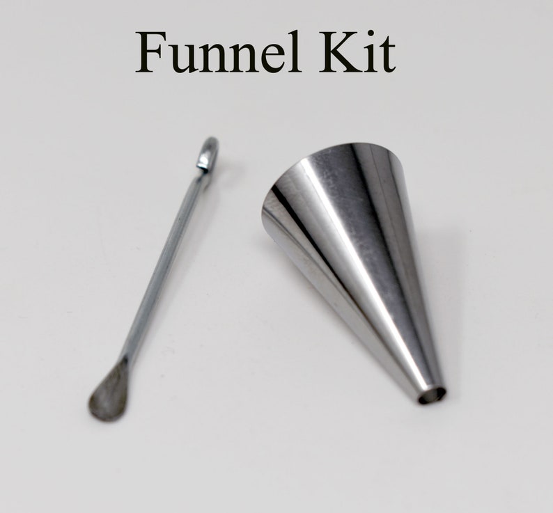 May include: A stainless steel funnel kit with the text "Funnel Kit" at the top. The kit includes a conical funnel and a small, long spoon-like tool. The funnel is silver and has a narrow opening at the bottom.