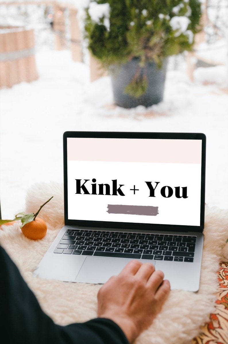 May include: A laptop computer with a white background on the screen. The text "Kink + You" is displayed in black bold font on the screen. A person's hand is resting on the trackpad.