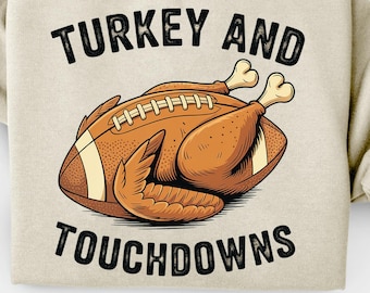 Könnte beinhalten: Beiges Sweatshirt mit den schwarzen Worten "TURKEY AND TOUCHDOWNS". Die Grafik zeigt einen gebratenen Truthahn in Form eines Footballs. Ostereier und ein Korb befinden sich im Hintergrund.