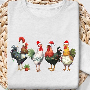Puede incluir: Una camiseta blanca de manga larga con un gráfico de cuatro gallos con gorros de Papá Noel y luces de Navidad. Los gallos están de pie en fila y mirando hacia adelante.