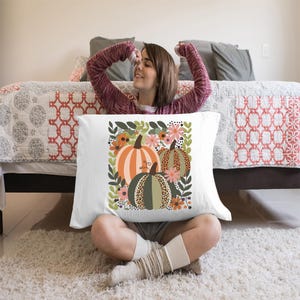 Pu&ograve; includere: Cuscino bianco con un design floreale colorato con tre zucche. Le zucche sono arancioni, verdi e marroni con un motivo leopardato.