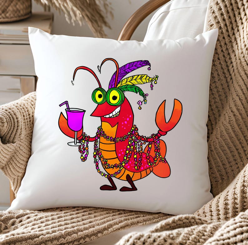 May include: White square throw pillow featuring a cartoon crawfish with a cocktail. The crawfish is red, orange, and yellow, wearing Mardi Gras beads and a feathered headdress. It holds a purple drink with a straw.