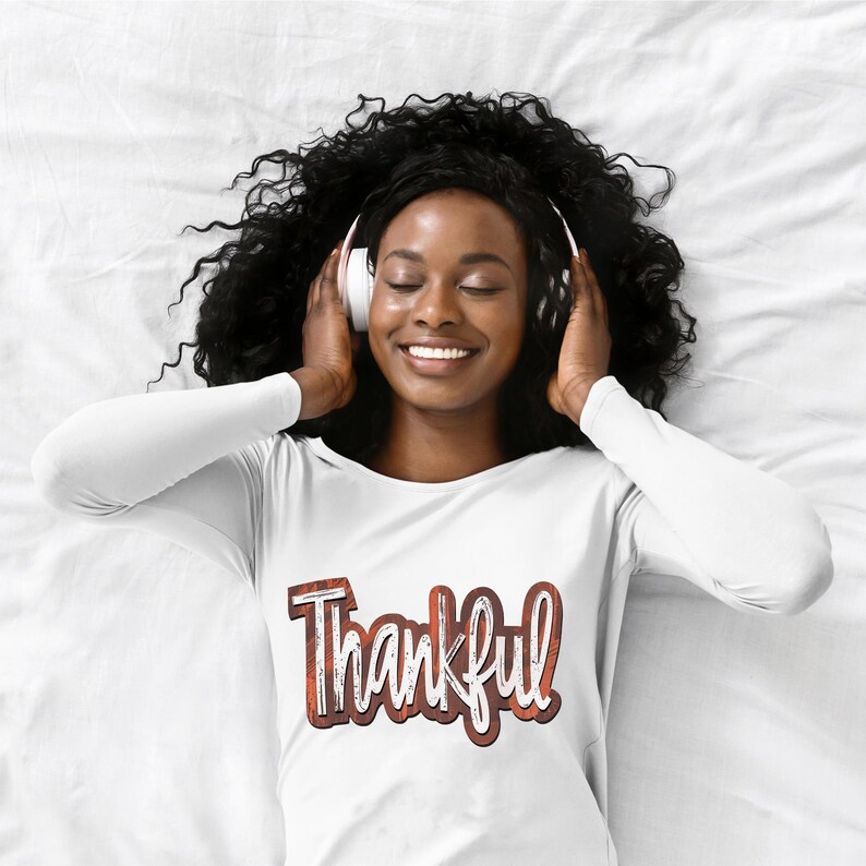K&ouml;nnte beinhalten: Ein wei&szlig;es Langarmshirt mit dem Wort "Thankful" in brauner und wei&szlig;er, abgenutzter Schrift.