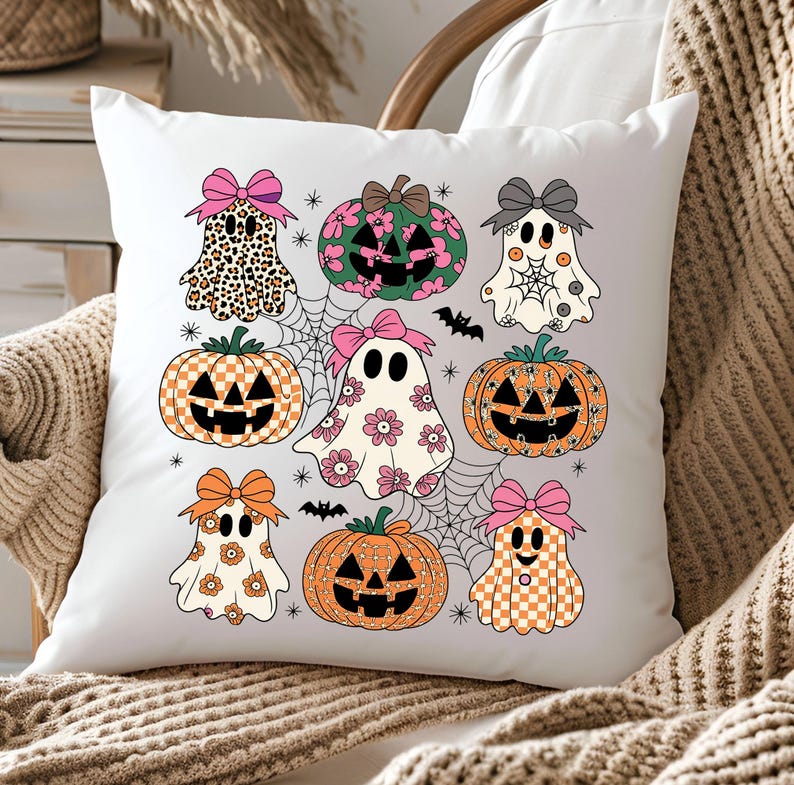May include: White square pillow featuring a Halloween-themed design. The design includes cartoon ghosts, pumpkins, spiderwebs, and bats. The ghosts and pumpkins are decorated with patterns and bows in various colors, including pink, orange, and black. The pillow is on a neutral-toned surface.
