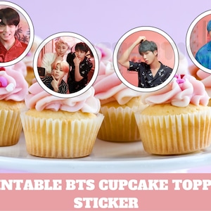 May include: Cupcakes with pink frosting and circular images of people. The cupcakes are on a white platter. The text at the bottom reads "PRINTABLE BTS CUPCAKE TOPPER / STICKER".