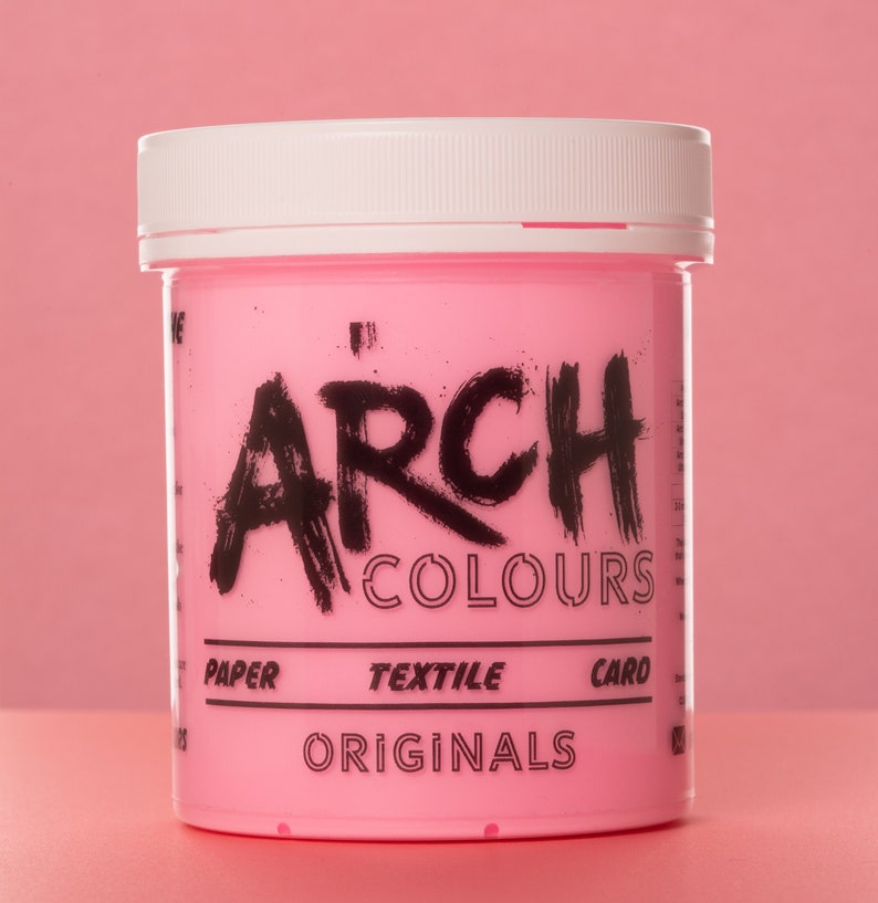 May include: A pink plastic container of hair dye with a white lid. The container has black text that reads "ARCH COLOURS ORIGINALS" and "PAPER TEXTILE CARD".