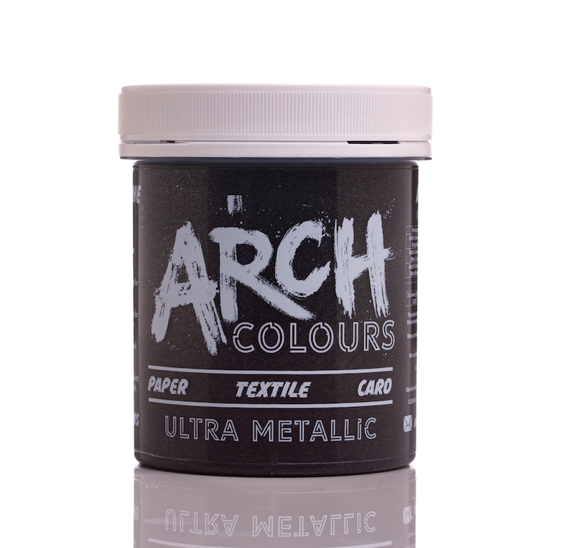 May include: A black jar of paint with a white lid. The jar is labeled "Arch Colours Ultra Metallic" and has the words "Paper, Textile, Card" printed on it.
