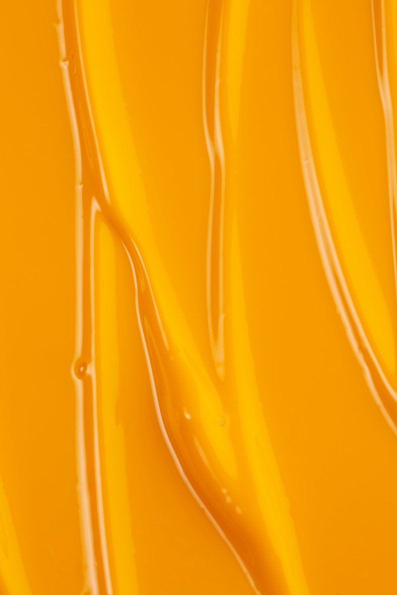 May include: Close-up of a smooth, bright yellow surface with a rippled texture. The surface is shiny and reflects light.