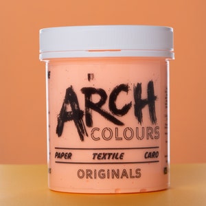 May include: A peach-colored jar of paint with a white lid. The jar is labeled "ARCH COLOURS" in black lettering. The label also says "PAPER, TEXTILE, CARD" and "ORIGINALS".