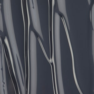 May include: Close-up of a dark gray, glossy, liquid with a smooth, flowing texture. The liquid has a slightly metallic sheen and creates a rippling effect.